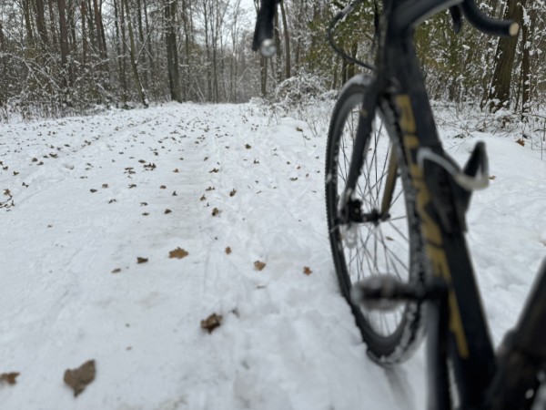 A bicycle partially visible on the right side of the frame on a snow-covered path with trees in the background.

Rower częściowo widoczny po prawej stronie kadru na ośnieżonej ścieżce z drzewami w tle.