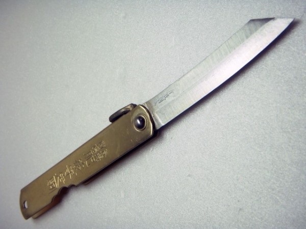 A traditional Japanese pocket knife, the Higonokami, an 80mm version shown opened up, with (presumably) a brass handle and carbon steel blade.