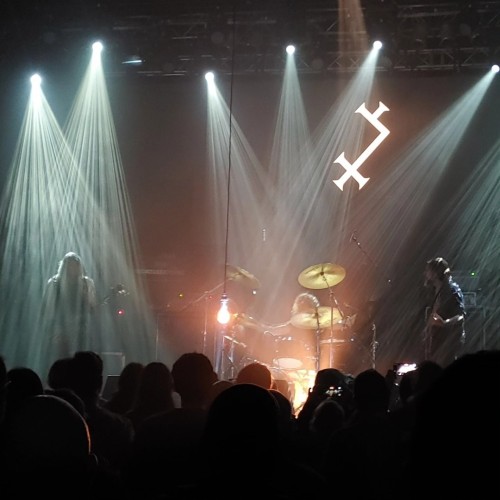 trio muzyków na scenie, pośrodku żarówka