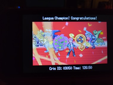 a picture of a 3DS screen showing a Pokémon trainer in the middle and three Pokémon on each side. From left to right, bastiodon, garchomp, spiritomb, rotom fan, toxicroak, and the blue and green variant of gastrodon. There's confetti falling, and at the top of the screen it says "League Champion! Congratulations!" and at the bottom it says "Cris ID 03050 Time: 126:50"