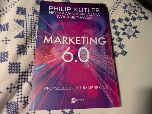 Zdjęcie książki "Marketing 6.0: przyszłość jest immersyjna" autorstwa trojga autorów - Philipa Kotlera, Hermawana Kartajai oraz Iwana Setiawana. Na okładce widnieje wielki tytuł "Marketing 6.0", kolory są od czerwonego przez różowy do fioletowego i przypomina to wielki wybuch.