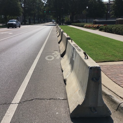 A bike lane obstructed with a line of temporary concrete Jersey barriers parallel to the curb