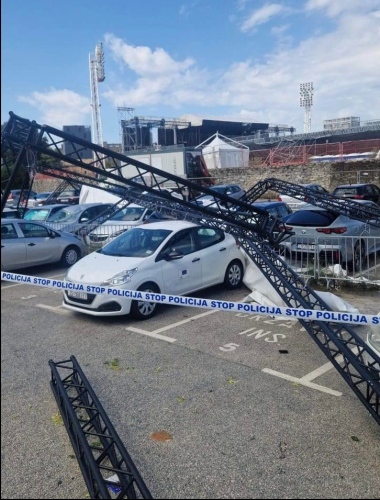 zdjęcie białego samochodu na parkingu, przygniecionego konstrukcją stalową, która miała tworzyć elementy sceny