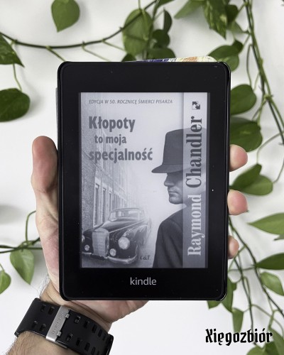 Czytnik Kindle wyświetlający okładkę książki "Kłopoty to moja specjalność" Raymonda Chandlera.